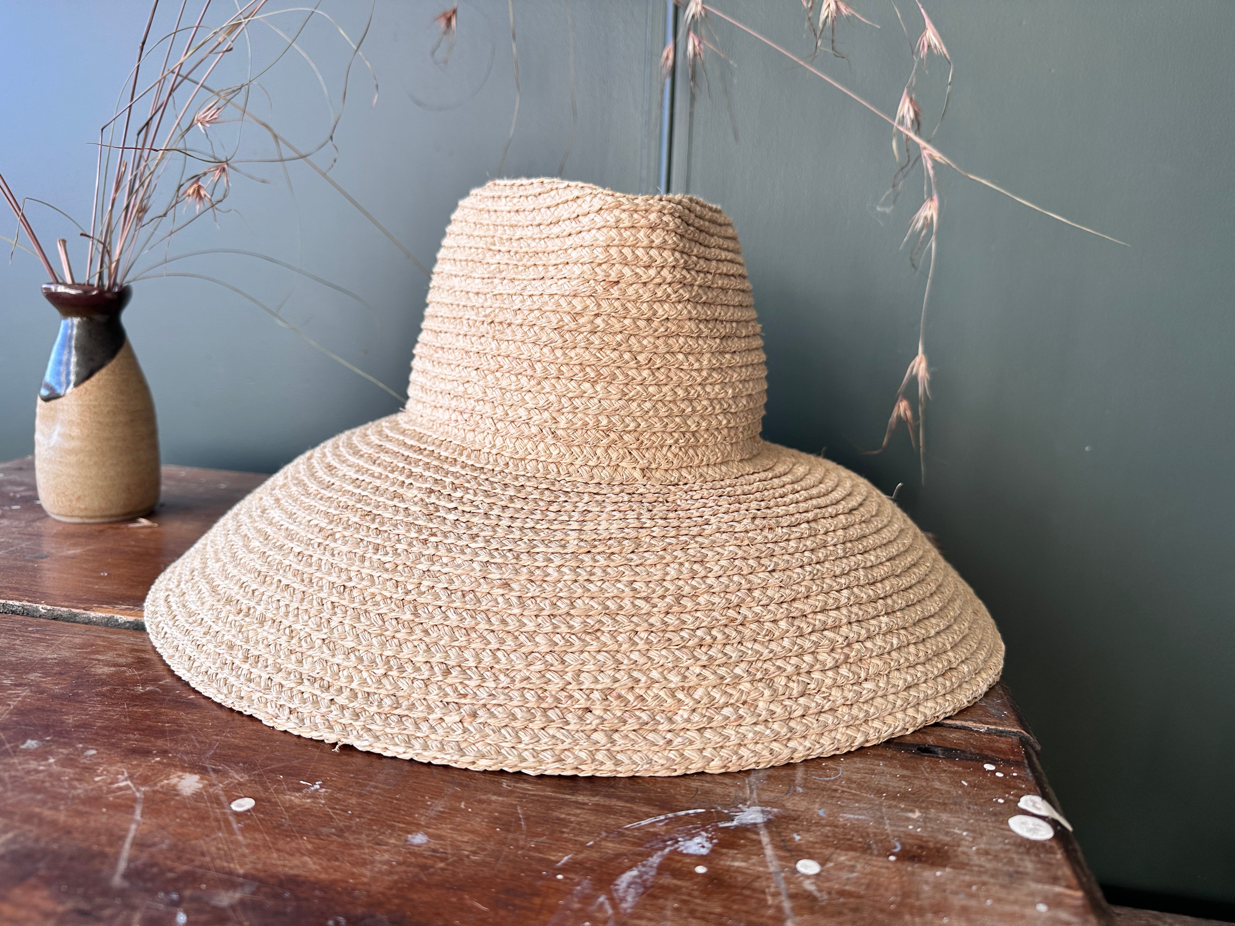 Woven hat on a wooden surface with a neutral background
